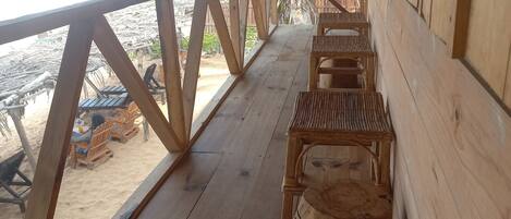 A wooden deck with a railing overlooking a beach.