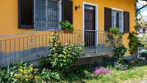 A yellow building with three windows, a door, and a small balcony with a metal railing. - Nice apartment for 2 people with WIFI, pool, A/C, terrace, pets allowed and panoramic view (Vinchio)