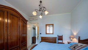 A bedroom with a large bed, wooden wardrobe, a dresser, a chair, and a bedside table with a lamp. - Nice apartment for 2 people with WIFI, pool, A/C, terrace, pets allowed and panoramic view (Vinchio)