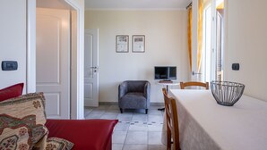 A compact living space with a dining area, a television, and a small table with a decorative bowl. - Nice apartment for 2 people with WIFI, pool, A/C, terrace, pets allowed and panoramic view (Vinchio)