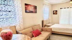 Ein Hotelzimmer mit Bett, Sofa, rundem Tisch mit Vase und einer Wand mit einem Gemälde.