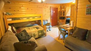 A cozy log cabin room with a bed, two sofas, a dining table, and a ceiling fan. - Deer Run is your perfect Mountaintop Cabin Equipped for Family Adventure! (Mena)