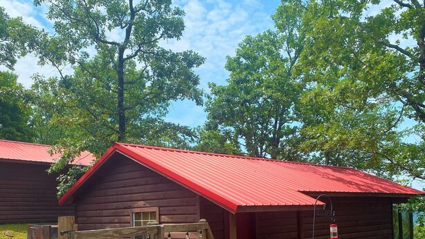 A rustic cabin with a red roof, a wooden deck, and a sign that reads "Deer Run". - Deer Run is your perfect Mountaintop Cabin Equipped for Family Adventure! (Mena)