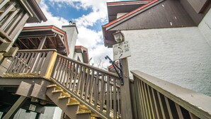 A wooden staircase leading to a building with a sign displaying apartment numbers.