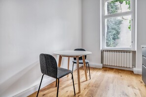 Enjoy a peaceful stay in this serene room with a round table, two chairs, and a large window offering a view of lush greenery.