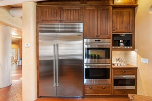 A stainless steel refrigerator with a freezer compartment, a built-in oven, and a microwave above it.