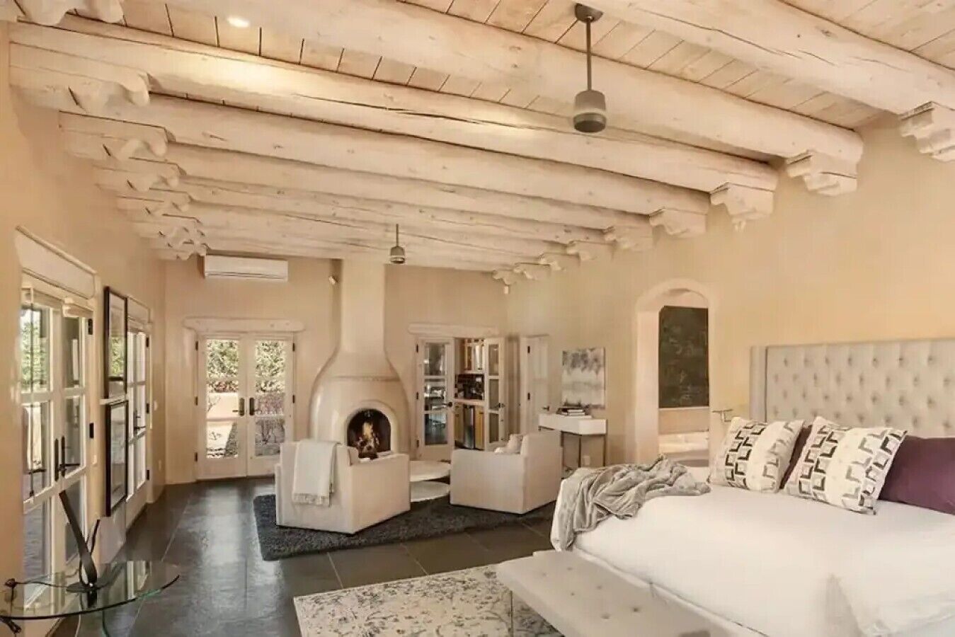 A bedroom with a fireplace, a bed, and a view of the outdoors.