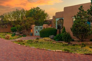 A residential area with a paved driveway, a gated entrance, and a building with stucco walls.