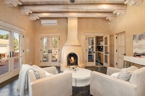 A cozy living room with a fireplace, white sofas, and a view of the outdoors.