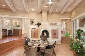 Un comedor con chimenea, una cocina con armarios de madera y una planta grande.