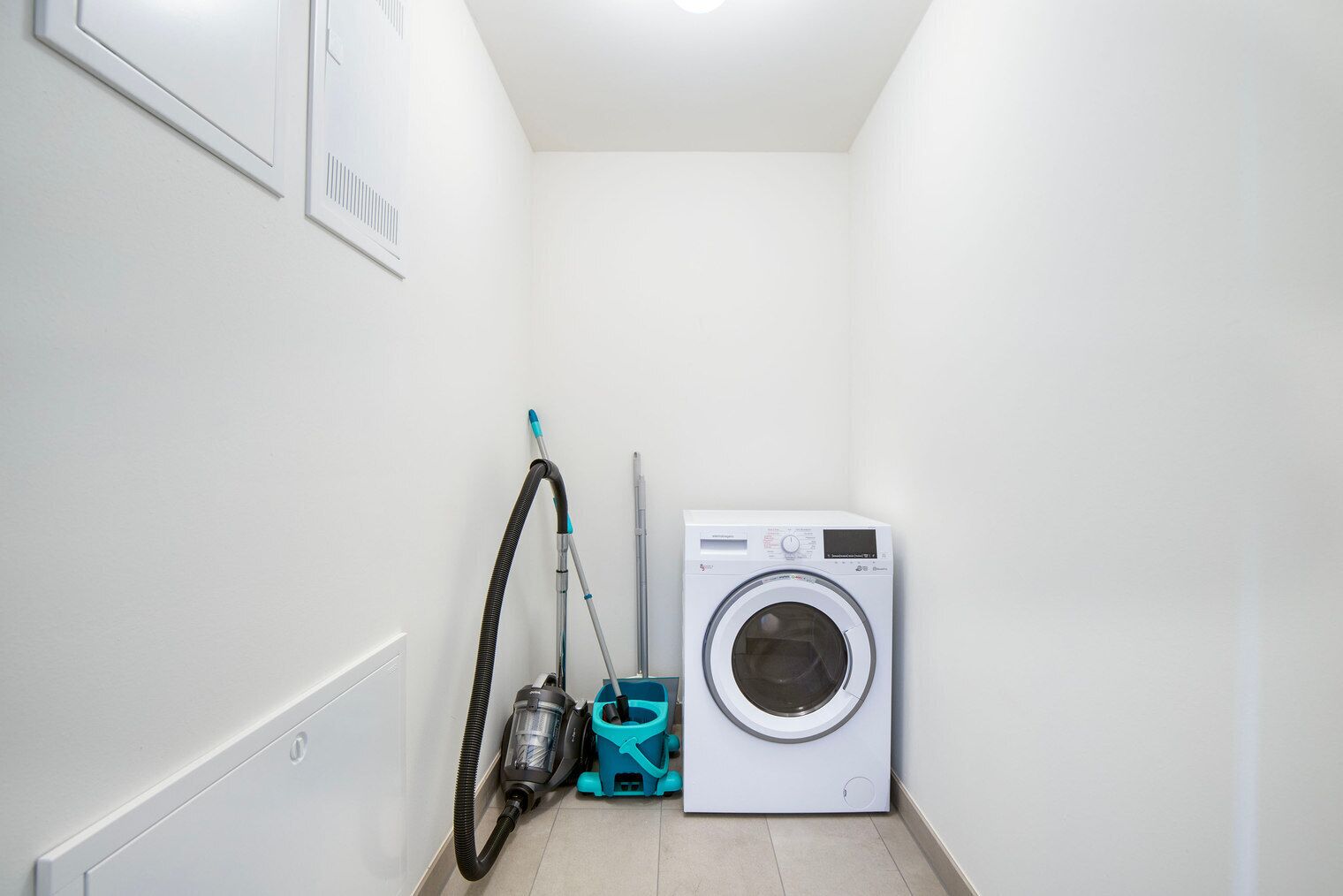 Une buanderie équipée d’un lave-linge et d’un aspirateur.