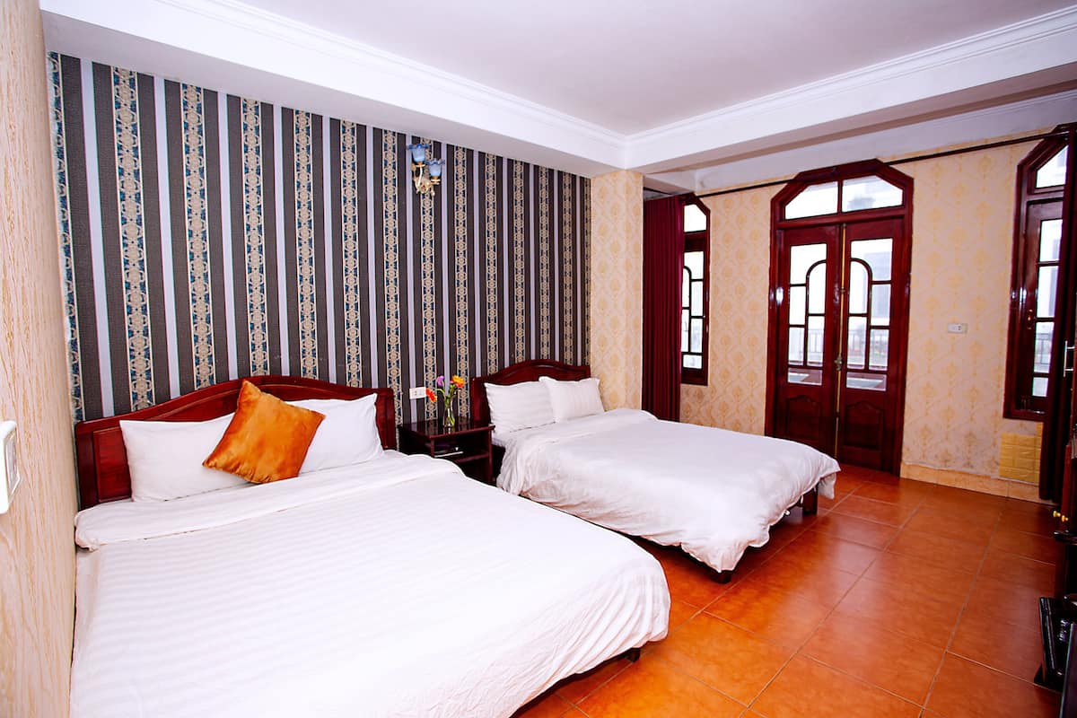 A hotel room with two beds, a nightstand, and a window with curtains.