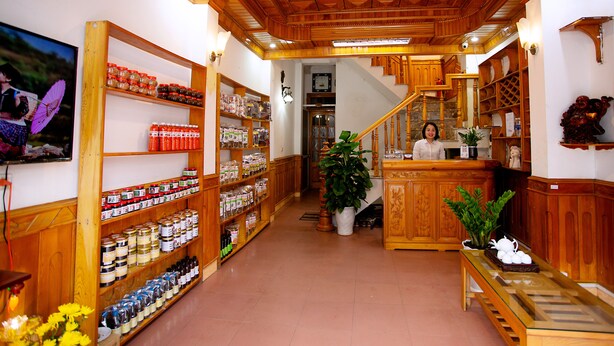 A reception area with wooden shelving stocked with various products, a staircase, and a receptionist.