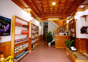 A reception area with wooden shelving stocked with various products, a staircase, and a receptionist.
