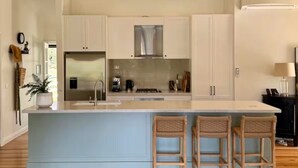 Eine Küche mit Kochinsel, Barhocker und Kühlschrank.
