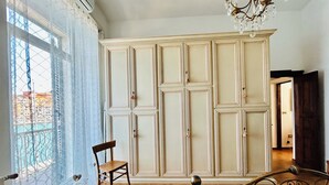Ein Schlafzimmer mit großem Kleiderschrank, einem Sessel, einem Bett und einer Chandelüster.