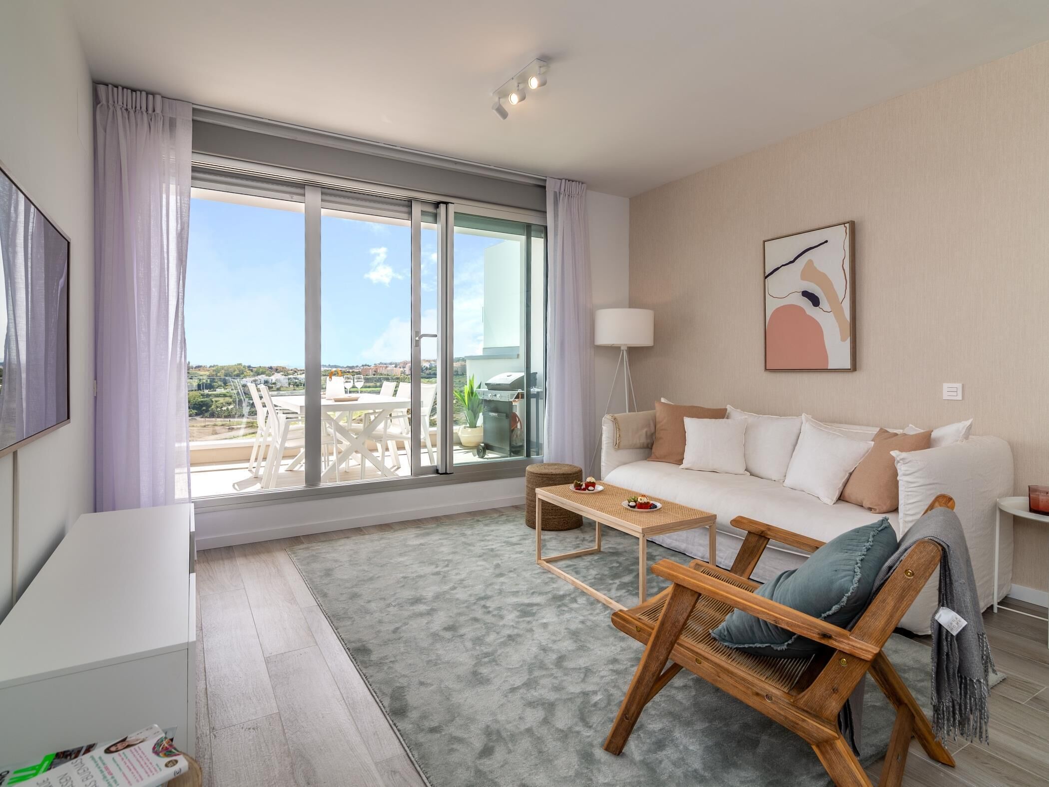 Un salon moderne comprenant un canapé, une chaise en bois, une petite table et une grande fenêtre donnant sur la ville.