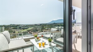 Un balcon avec une table dressée pour deux personnes, un canapé et une vue sur un paysage montagneux.