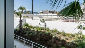 Un jardin sur le toit, agrémenté de diverses plantes et d’un palmier, qui offre une vue sur un ensemble d’immeubles modernes.