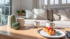 Una sala de estar acogedora con un sofá, cojines, una mesita de centro y un plato de comida.