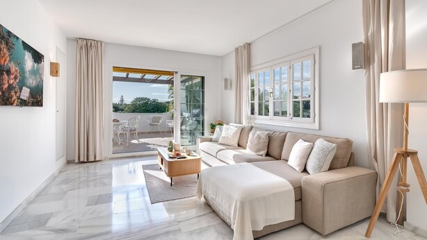 Una sala de estar moderna con un sofá, una mesa de centro y vistas a un patio exterior.