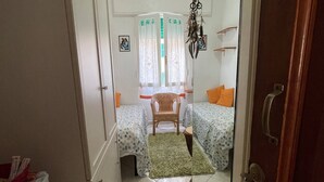 Un couloir étroit mène à une chambre à coucher qui contient deux lits, une petite table et une chaise.