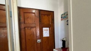 Un couloir avec des portes en bois, un sol carrelé et un mur blanc orné d’un petit tableau.
