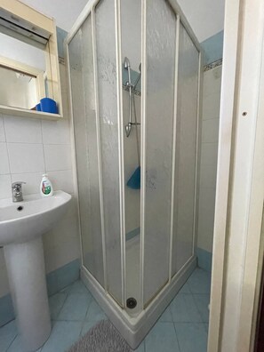 Een badkamer met een douchecabine, wastafel en spiegel.