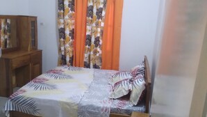 A bedroom with a bed, a wooden dresser, and a ceiling fan. - The Furnished Residences of Fasso Kanu -villa (Bamako)