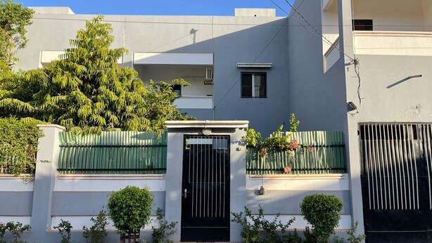 A two-story residential building with a black gate, green fencing, and potted plants. - The Furnished Residences of Fasso Kanu -villa (Bamako)