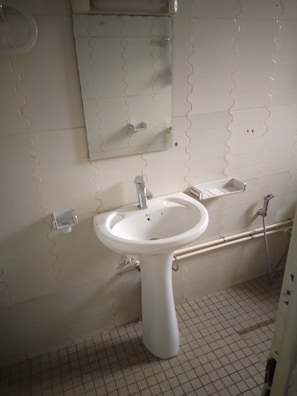 Casa de banho com lavatório branco, espelho e sanita.