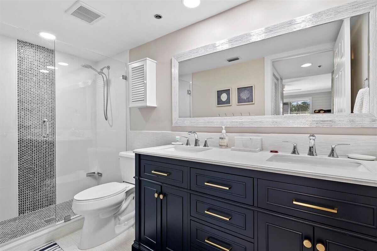 A modern bathroom with a walk-in shower, a toilet, a vanity with a large mirror, and a sink.
