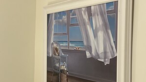 A painting of a room with a window overlooking the sea, a wicker chair, and a basket. - Private Modern Bedroom In a Central Location (Nantucket)