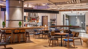 Un interior moderno con una zona de bar, asientos y una cocina al fondo.