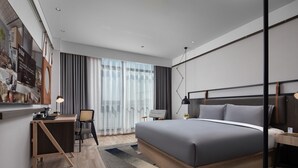A modern hotel room with a large bed, a desk, and a chair. There is a large window with curtains, a flat-screen TV mounted on the wall, and a small table with a lamp. - Shanghai Hongqiao NECC Glory Hotel (Shanghai)
