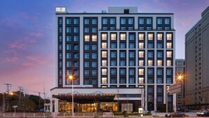 A modern hotel with a symmetrical facade, multiple floors, and a prominent entrance with a covered area. - Shanghai Hongqiao NECC Glory Hotel (Shanghai)
