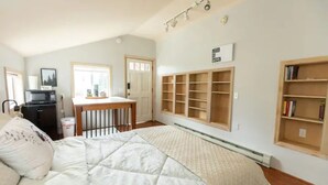 A bedroom with a bed, a desk, and built-in bookshelves.