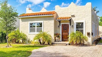 A stucco house with a tiled roof, a front door, and a small porch area.
