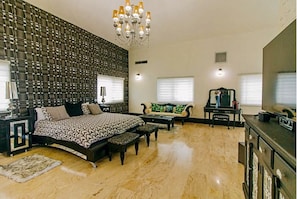 A bedroom with a bed, a sofa, a coffee table, and a TV.