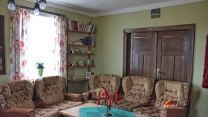 A living room with floral-patterned sofas, a wooden coffee table, and a bookshelf against the wall. - Old Authentic Icelandic Farmhouse (Fossholl Thingeyjarsveit)