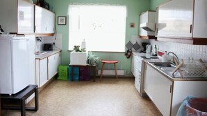 A compact kitchen with white cabinets, a refrigerator, a sink, and a window with a view. - Old Authentic Icelandic Farmhouse (Fossholl Thingeyjarsveit)