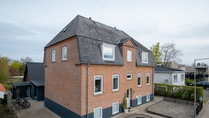 A two-story brick house with a dark roof, a small attached garage, and a paved driveway. - 1 Bed Apartment Sleeps 2 with Parking, WiFi, Tv (Aalborg)