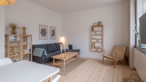 A modern living room with a sofa, coffee table, and shelves. - 1 Bed Apartment Sleeps 2 with Parking, WiFi, Tv (Aalborg)