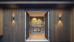 A wooden exterior with a stone fireplace and two wall-mounted lights.