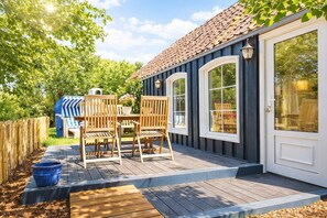 A deck with outdoor furniture, a grill, and a garden area. - Huus ant Dörpsdiek – Arrive. Breathe. Feel at Home. (Krummhörn)