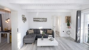 A modern living room with a sectional sofa, a coffee table, and a dining area with a table and chairs.