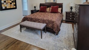 Un dormitorio con una cama grande, un banco, un aparador y un espejo.