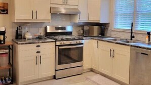 Una cocina moderna con armarios blancos, estufa de acero inoxidable y lavavajillas.