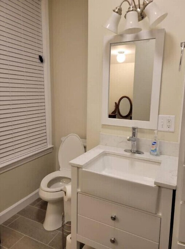 A bathroom with a toilet, a sink, and a mirror.