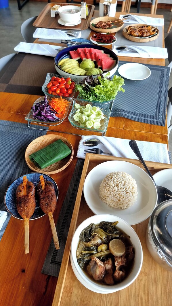 A table set with various dishes including rice, meat skewers, and a bowl of soup. - Destino Hotel Surin (Surin)